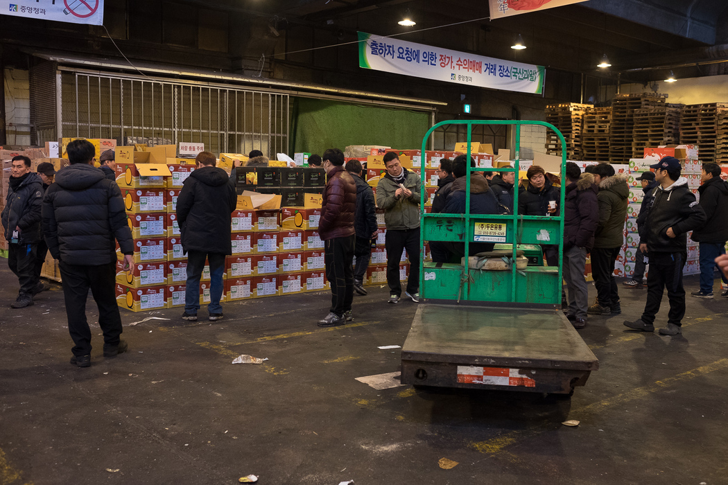 Potential buyers examine fruit before the beginning of an auction inside the Garak market.