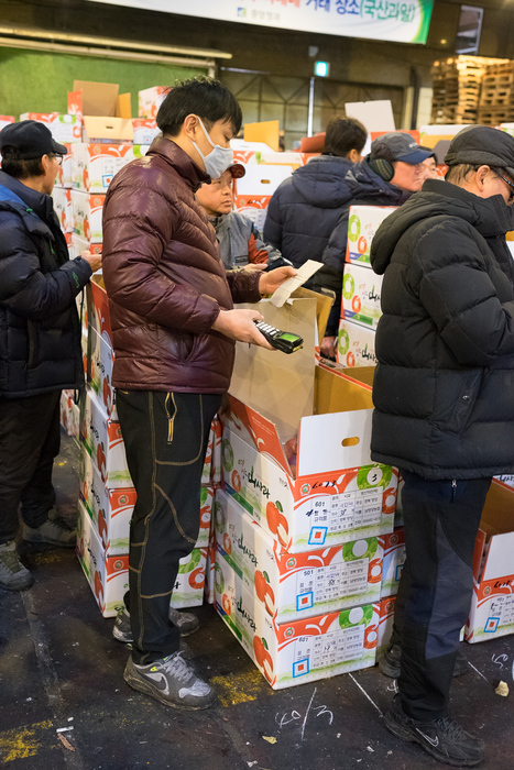 Buyers enter their bids on hand-held electronic devices at a fruit auction inside Garak Market, Seoul.