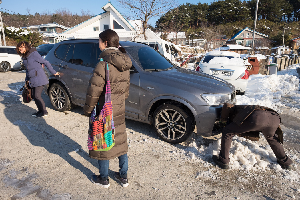 Kyung-ah's husband, Jong-ki, scraping snow from the car in preparation for the trip up to the punchbowl.